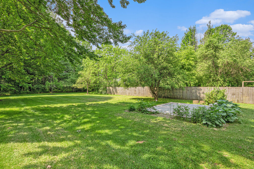 Spacious backyard with trees and wooden fence