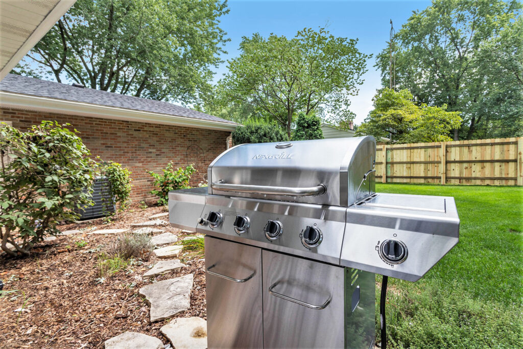 Stainless steel gas grill in backyard patio area
