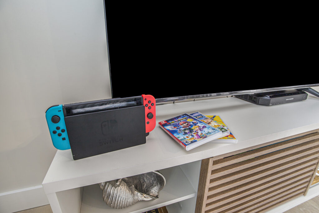 Nintendo Switch console and game cases on TV stand