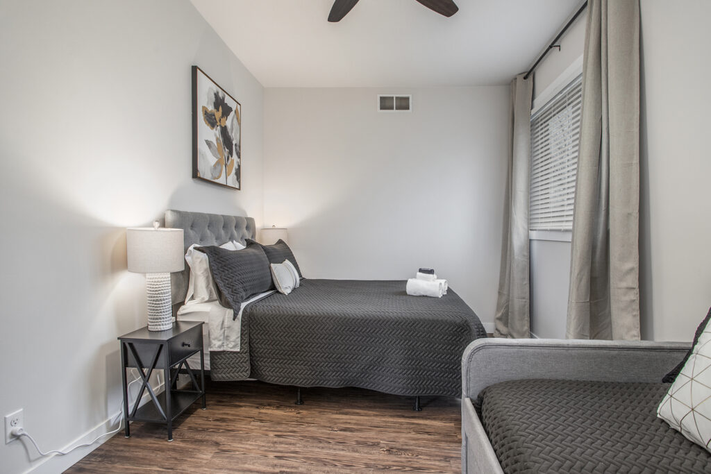 Modern bedroom with gray bedding and wood floor