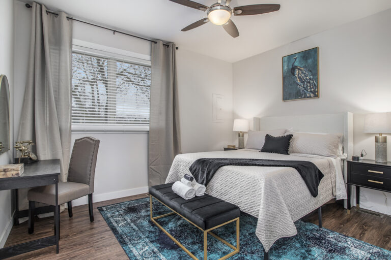 Modern bedroom with bed, desk, and ceiling fan