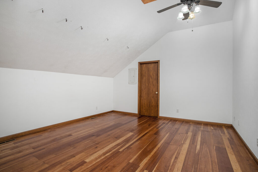 Empty attic room with wooden floor and ceiling fan
