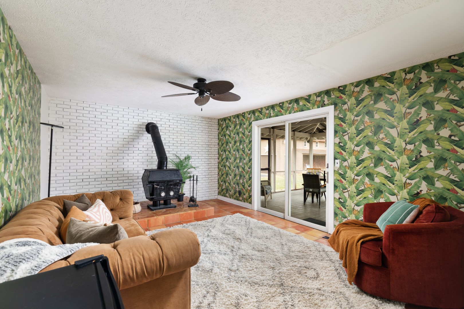Cozy living room with wood stove and tropical wallpaper