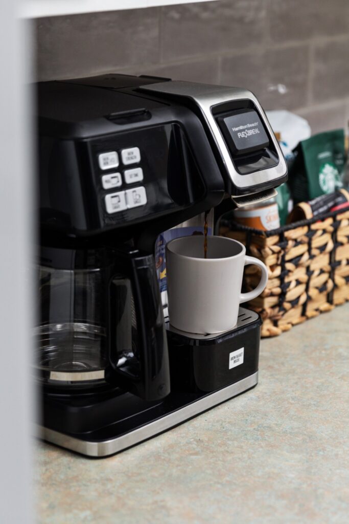 Coffee maker brewing coffee into white mug