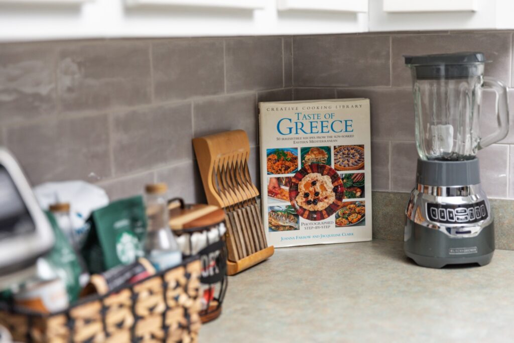 Greek cookbook beside blender on kitchen counter