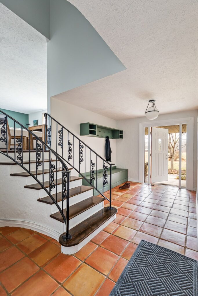 Bright entryway with staircase and terracotta tile floor