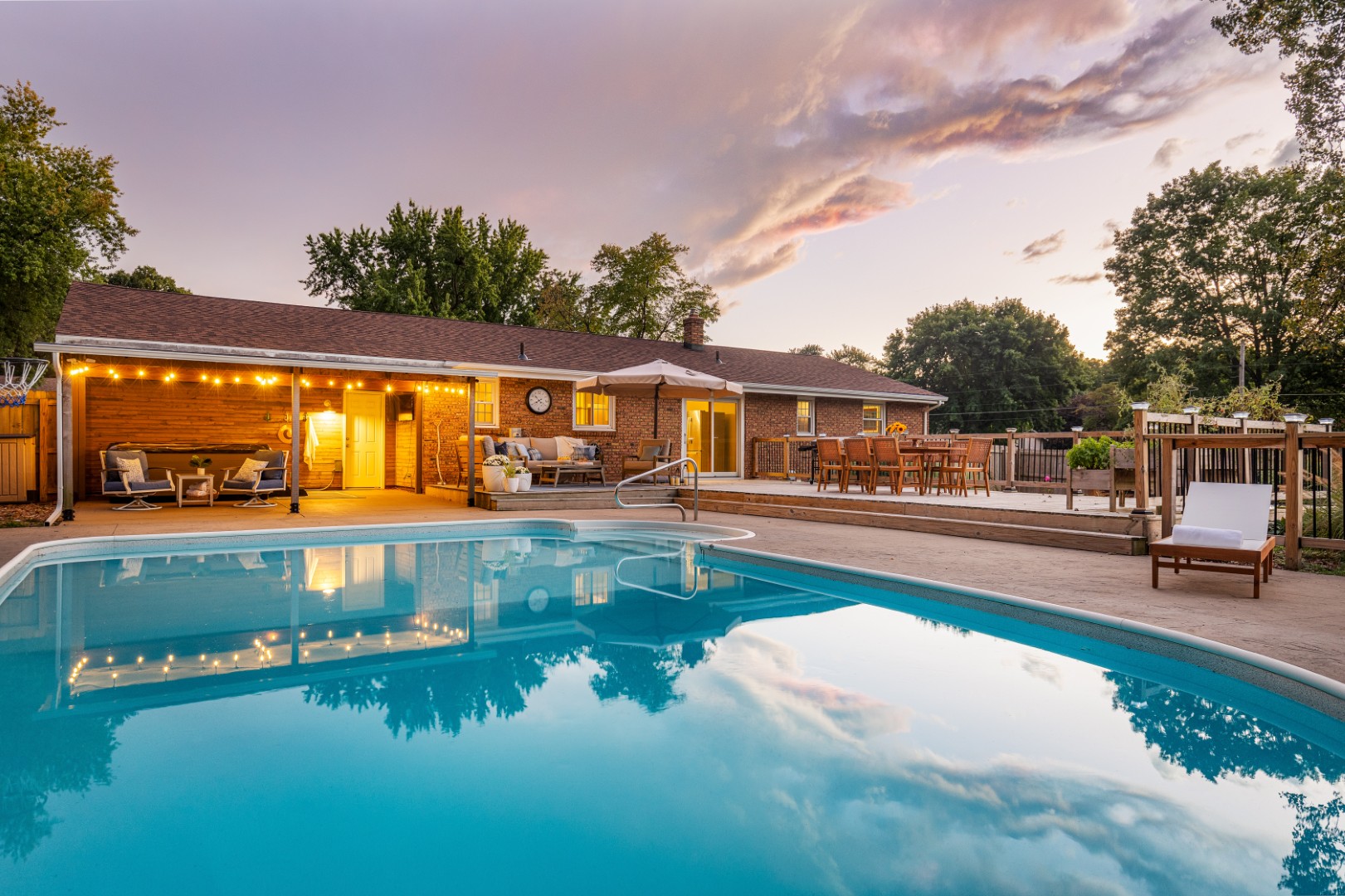 Backyard pool with patio seating at sunset
