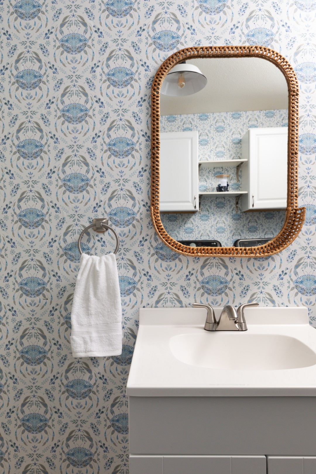 Bathroom sink with mirror and blue patterned wallpaper