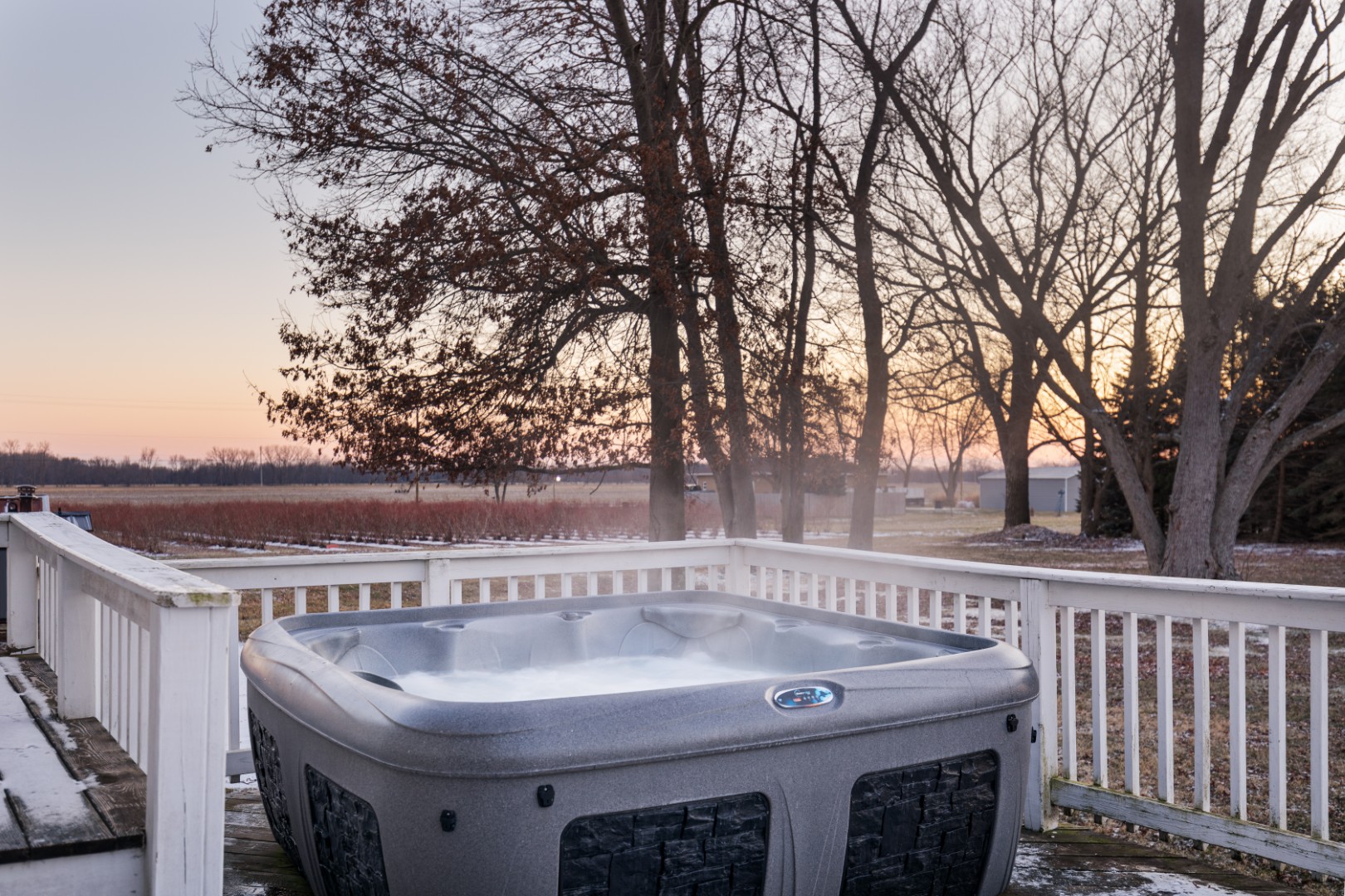 Outdoor hot tub on deck at sunset