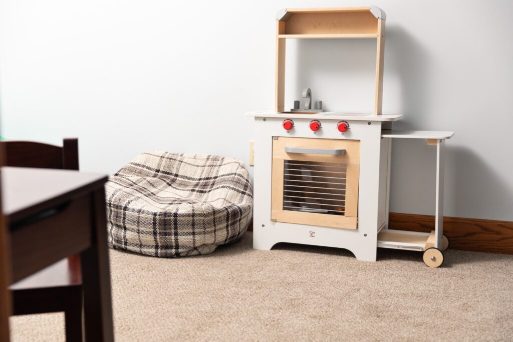 Toy kitchen set beside plaid bean bag