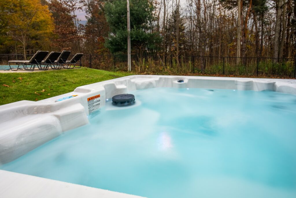Outdoor hot tub near forest and lounge chairs