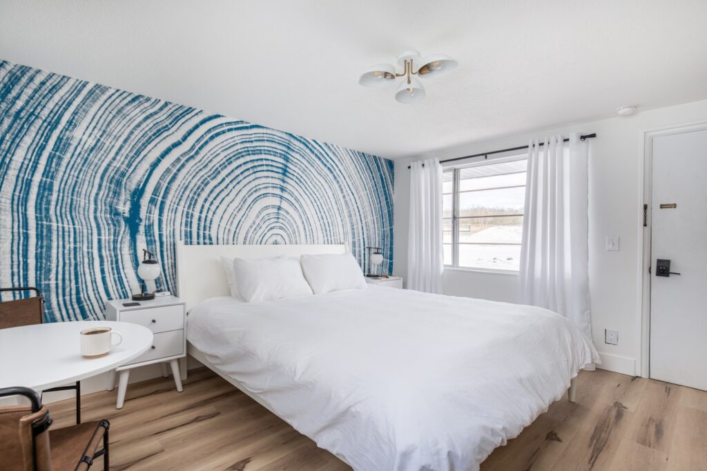 Modern bedroom with white bedding and blue mural