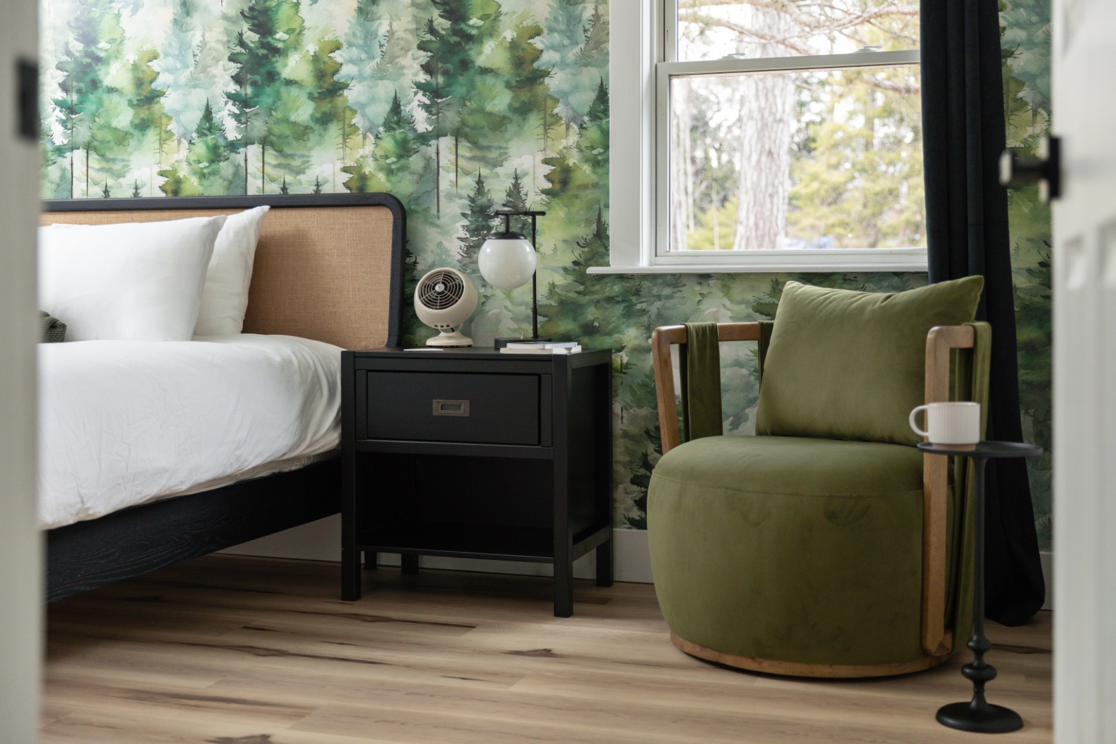 Cozy bedroom with forest-themed wallpaper and green chair