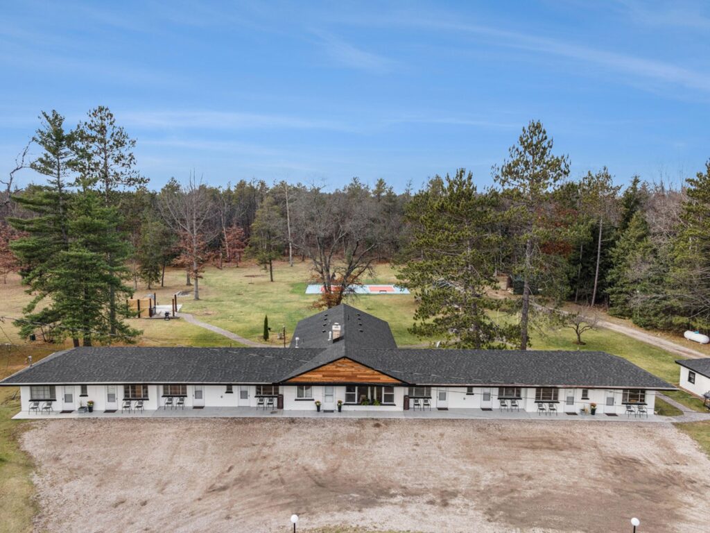 Single-story lodge surrounded by trees and open field