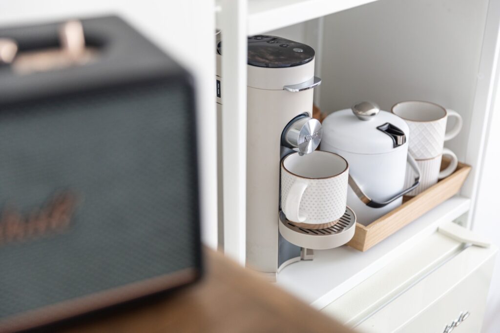 Coffee machine with mugs on kitchen shelf