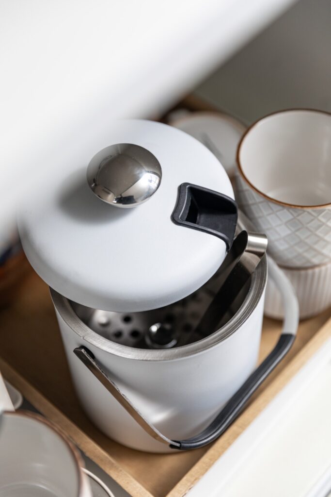 White French press coffee maker on shelf