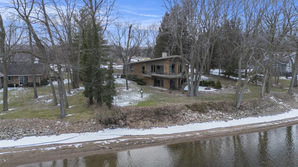 Lakeside house surrounded by trees in winter