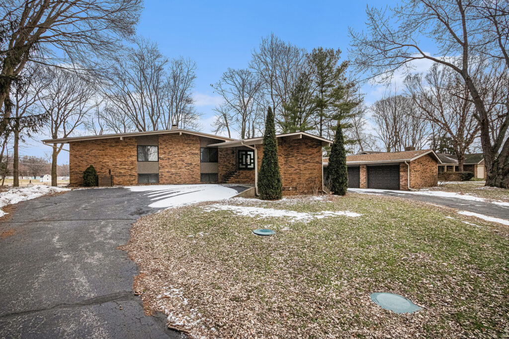 Brick house with driveway and garage in winter