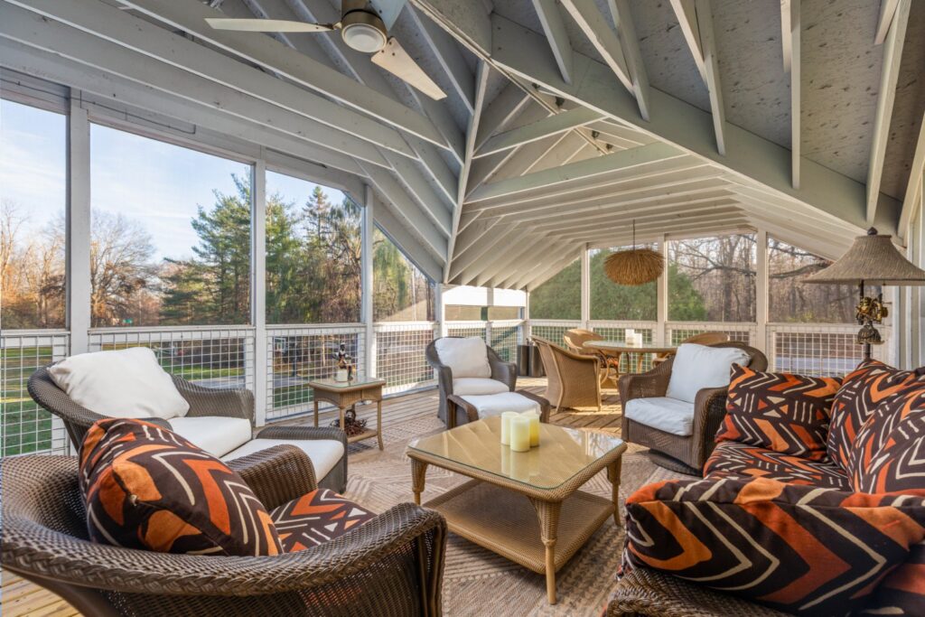 Cozy screened porch with wicker furniture and trees view