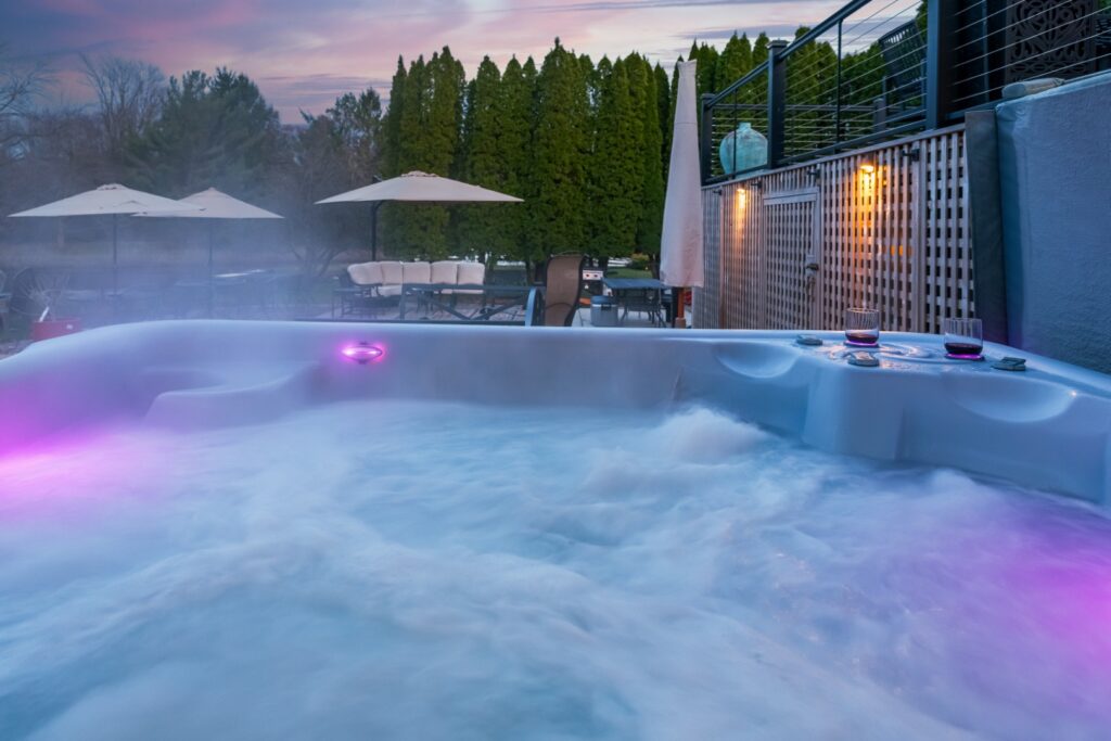 Outdoor hot tub with glowing lights at sunset