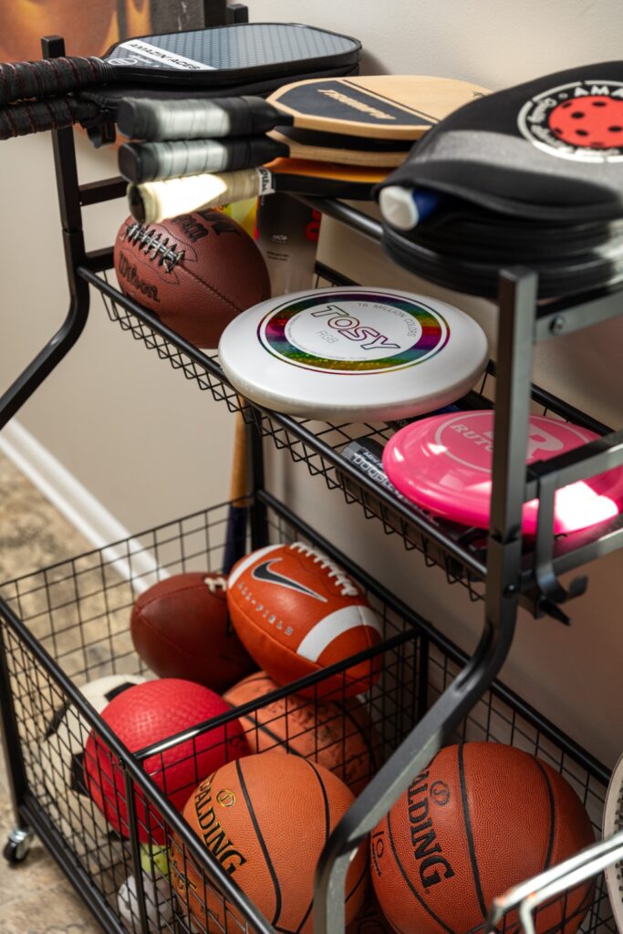 Rack with various sports balls and paddles