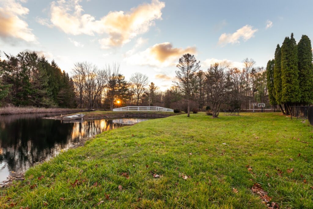 Sunset over pond and grassy backyard