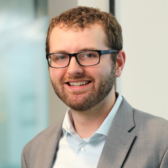 Smiling man wearing glasses and a gray suit