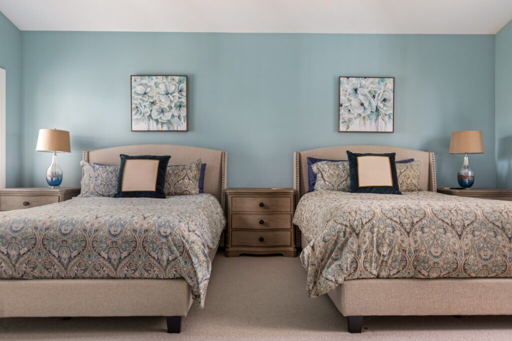 Modern bedroom with two matching beds and paintings