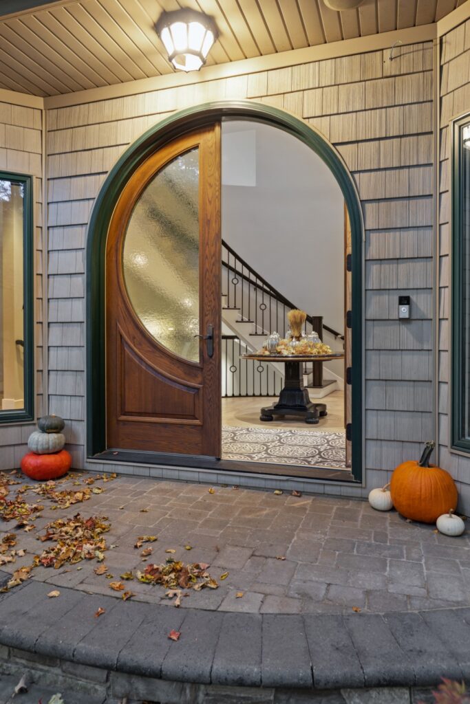 Autumn-themed front entry with pumpkins and open door