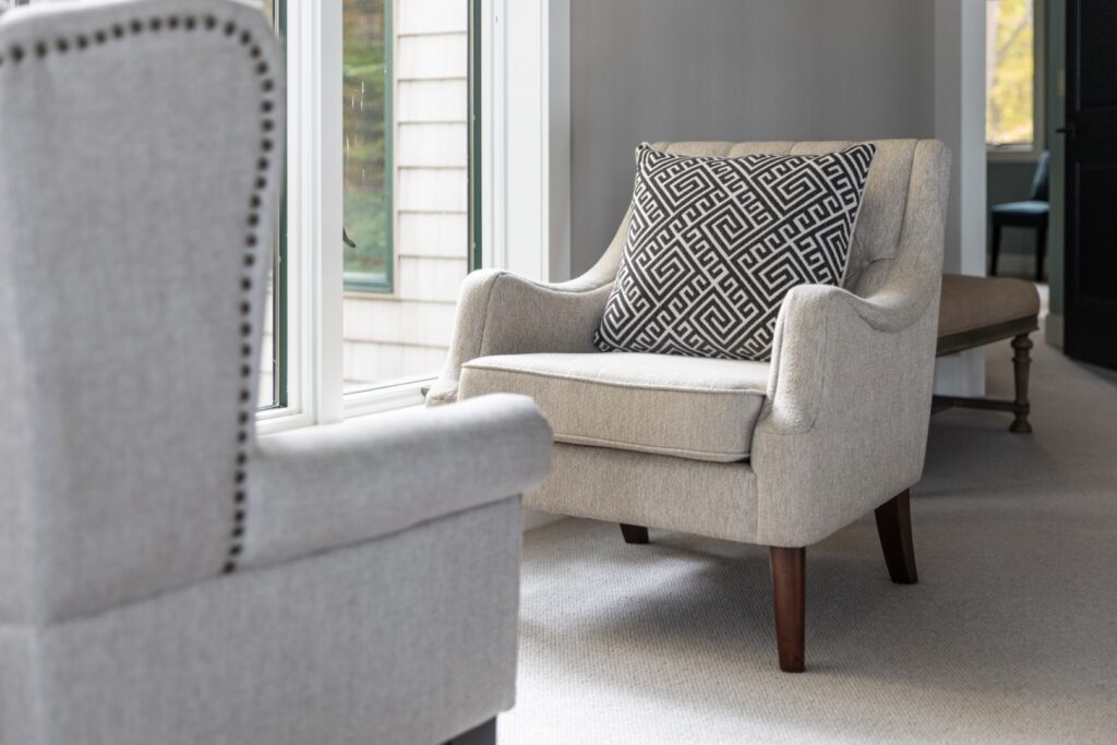 Beige armchair with patterned pillow by window