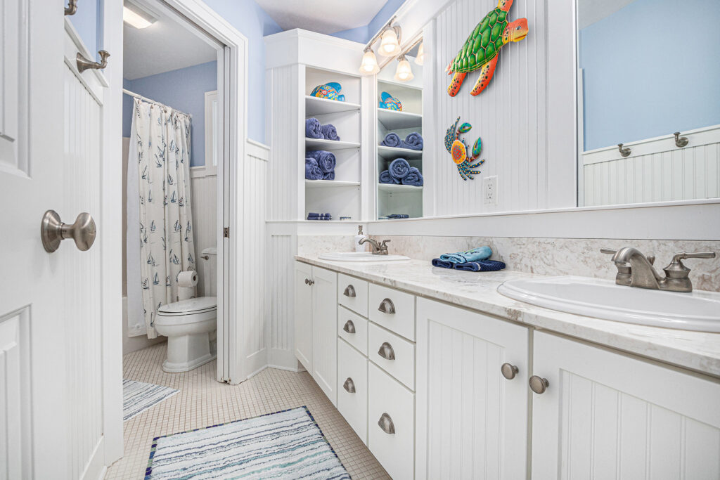 Coastal-themed bathroom with white cabinets and blue decor