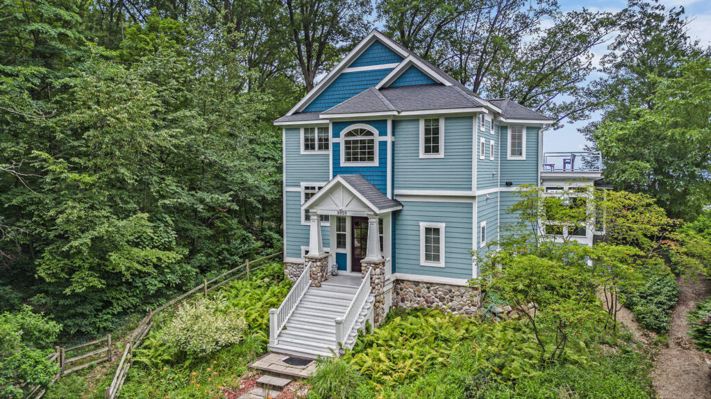 Blue two-story house surrounded by lush greenery