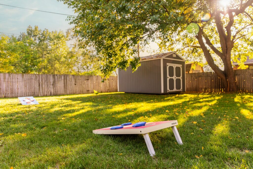 Backyard cornhole setup near shed on sunny day