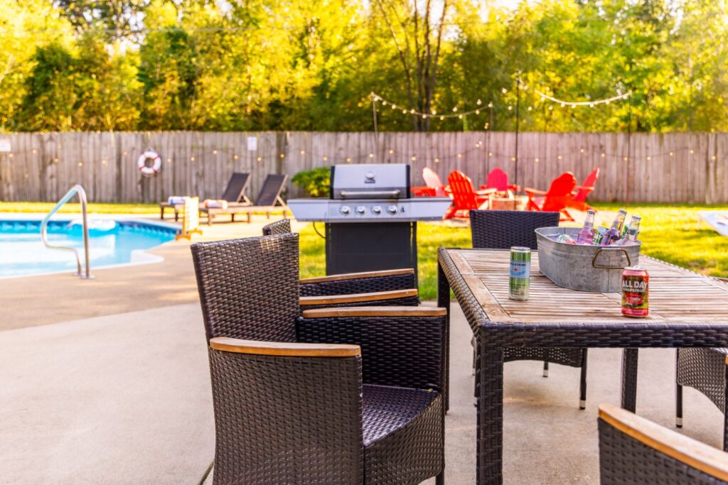 Backyard patio with pool, grill, and chairs