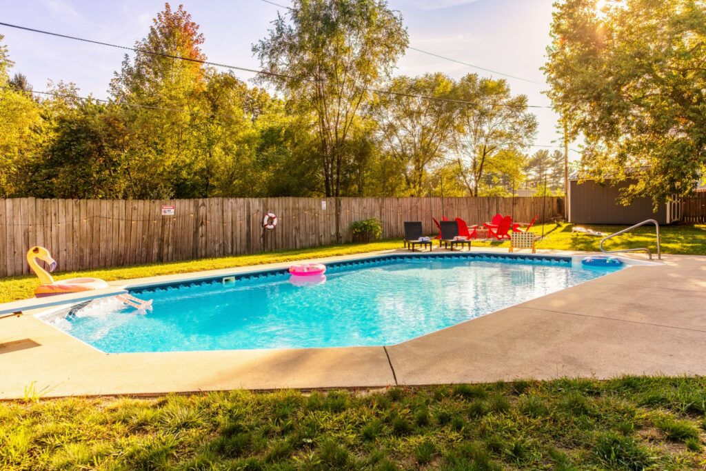 Backyard swimming pool with chairs and trees