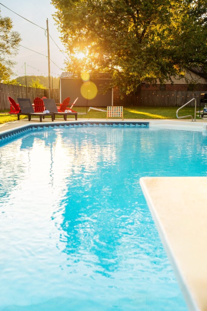 Sunny backyard pool with lounge chairs and trees