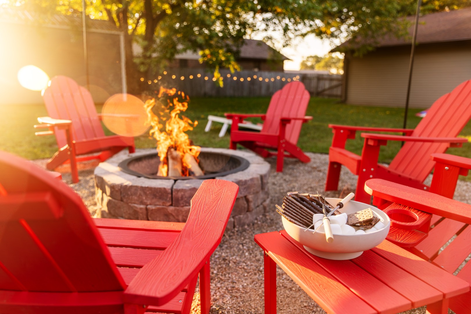 Backyard fire pit with red chairs at sunset