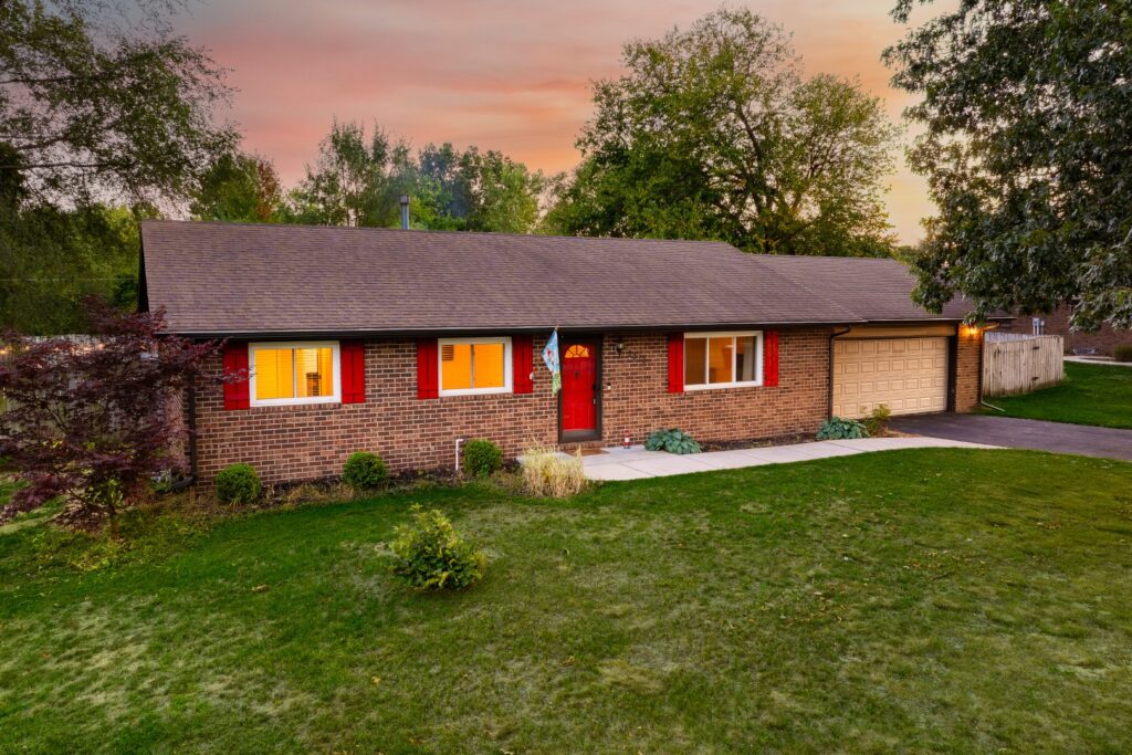 Brick house with red shutters at sunset