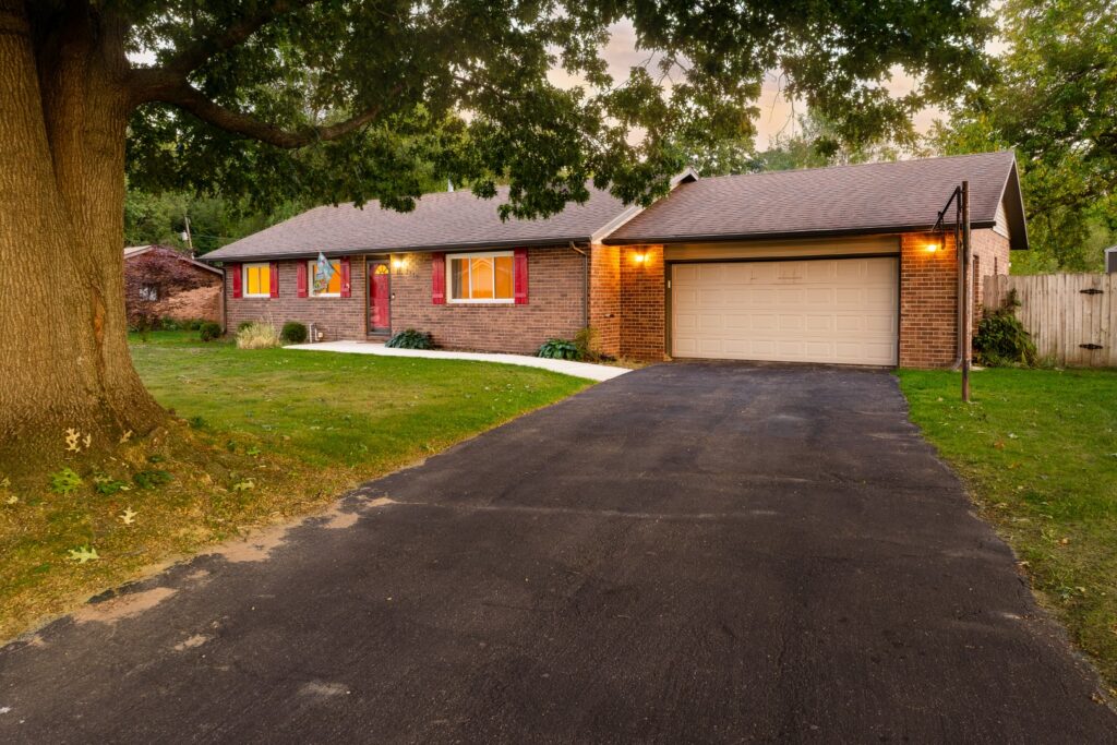 Brick house with driveway and garage at sunset