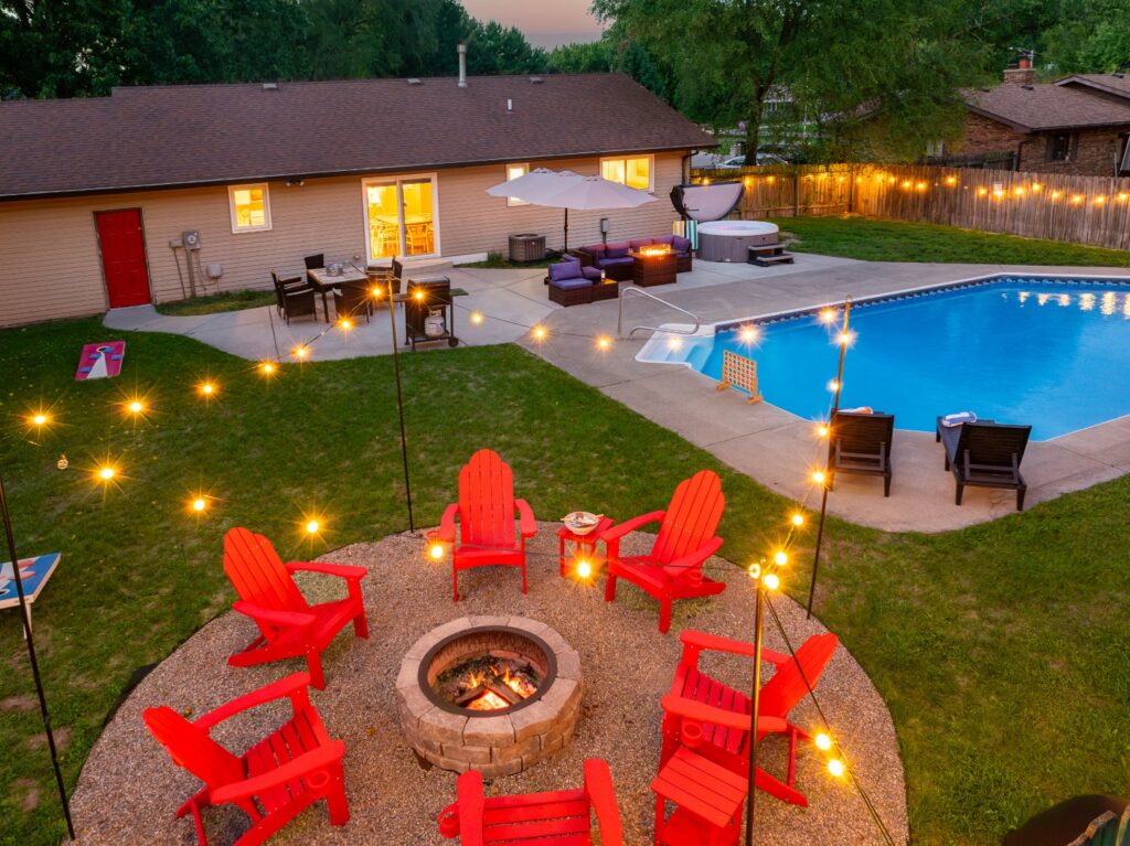 Backyard with pool, firepit, and red chairs at dusk