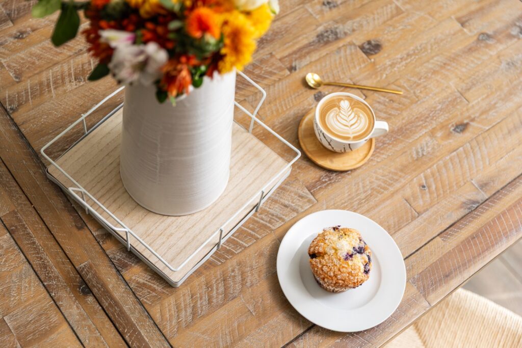 Latte and muffin on wooden table with flowers