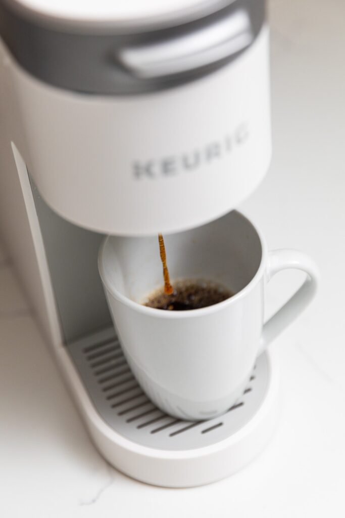 Coffee brewing into a white mug on machine