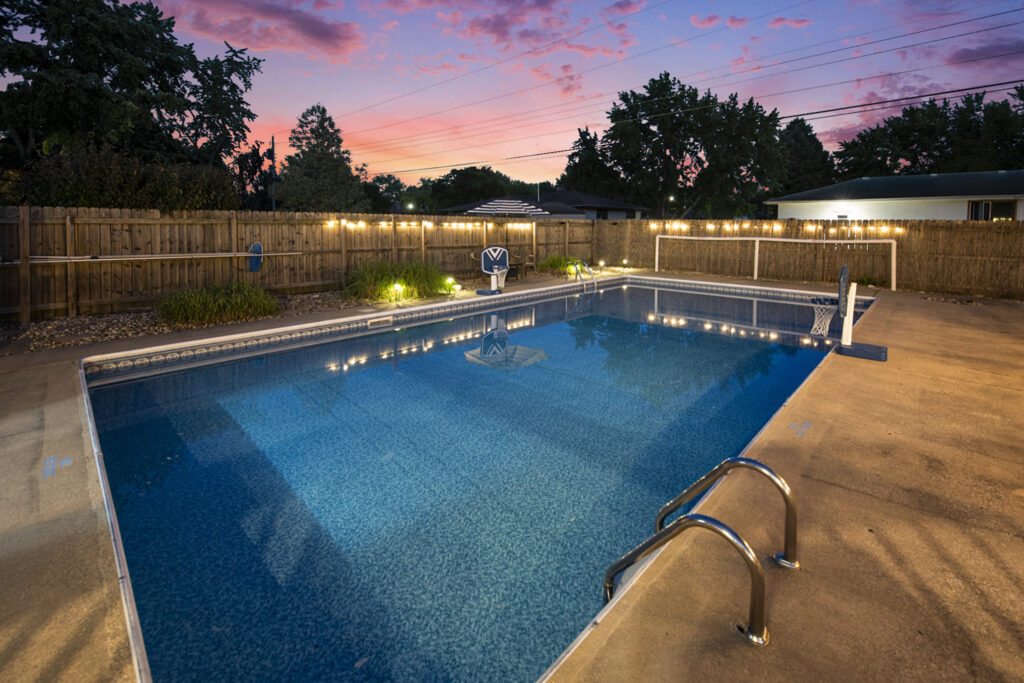 Backyard swimming pool at sunset with lights
