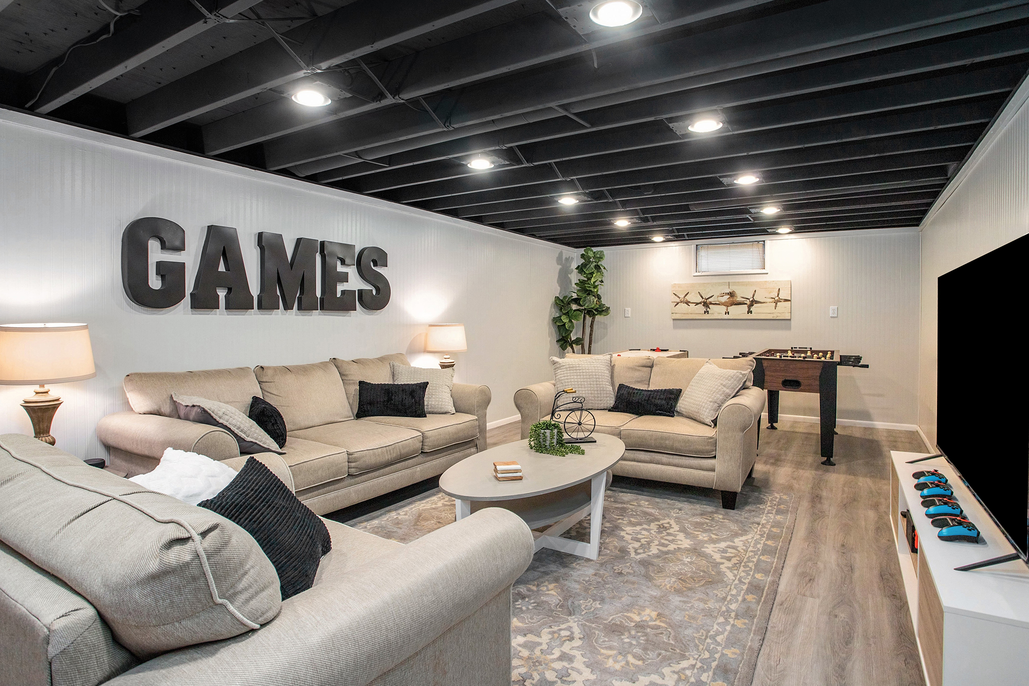 Modern basement game room with sofas and TV