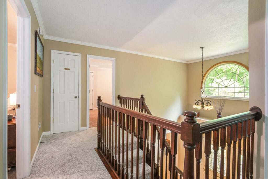 Upstairs hallway with railing and arched window