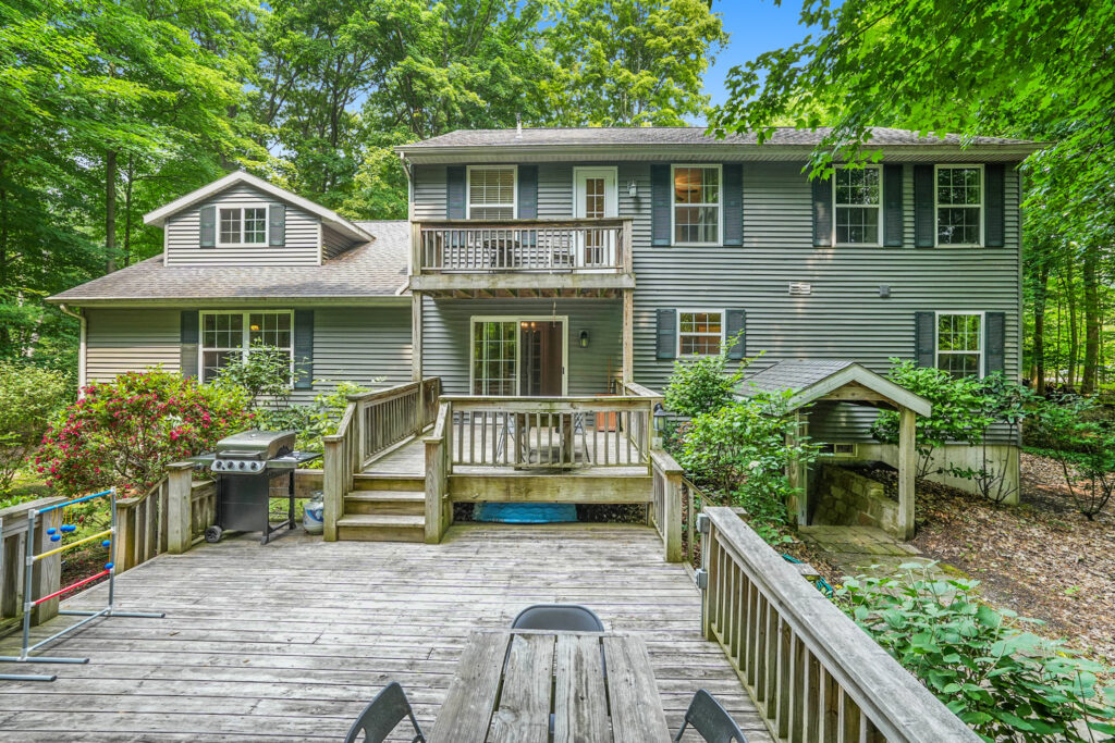 Two-story house with wooden deck and forest view