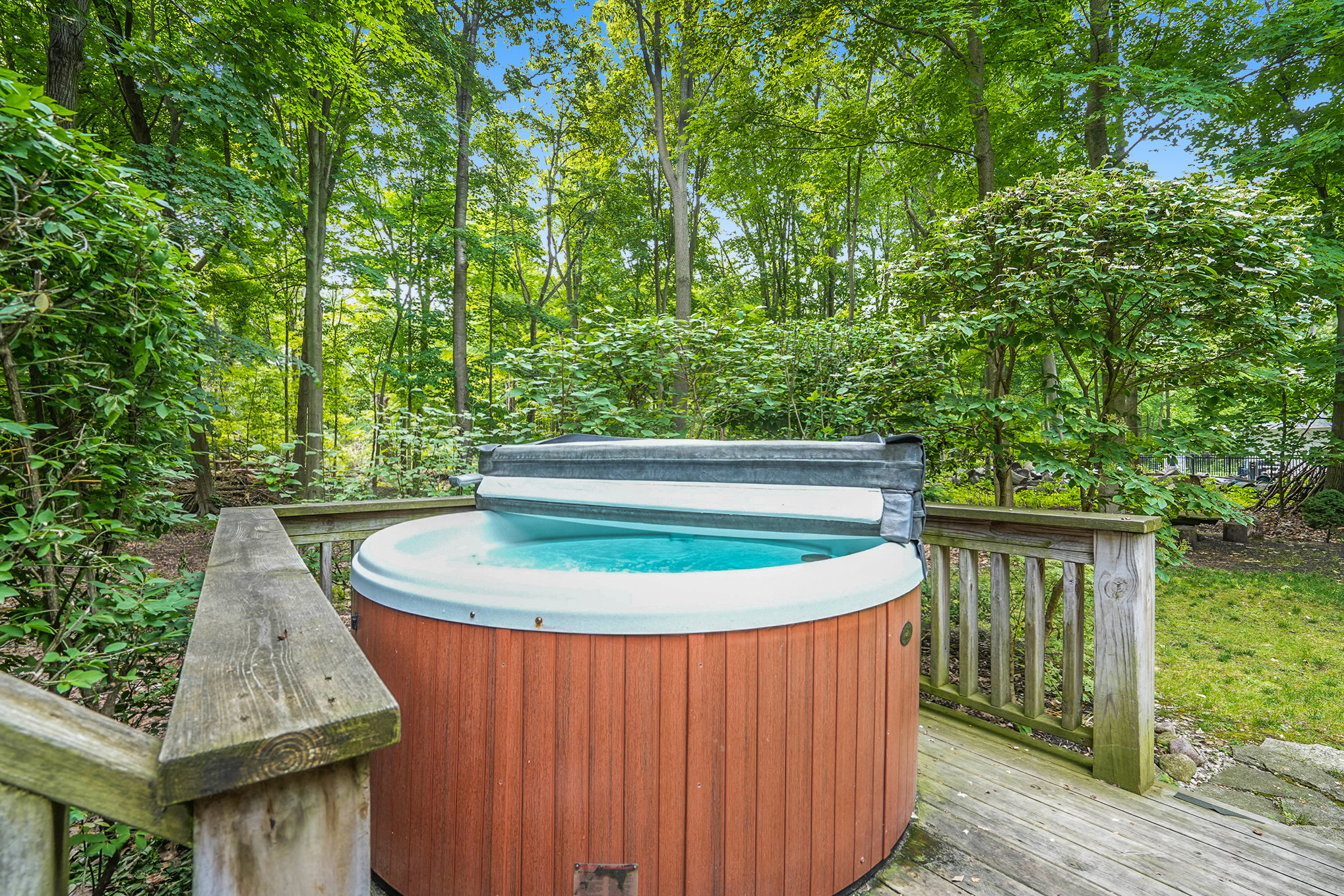 Outdoor hot tub on wooden deck surrounded by trees