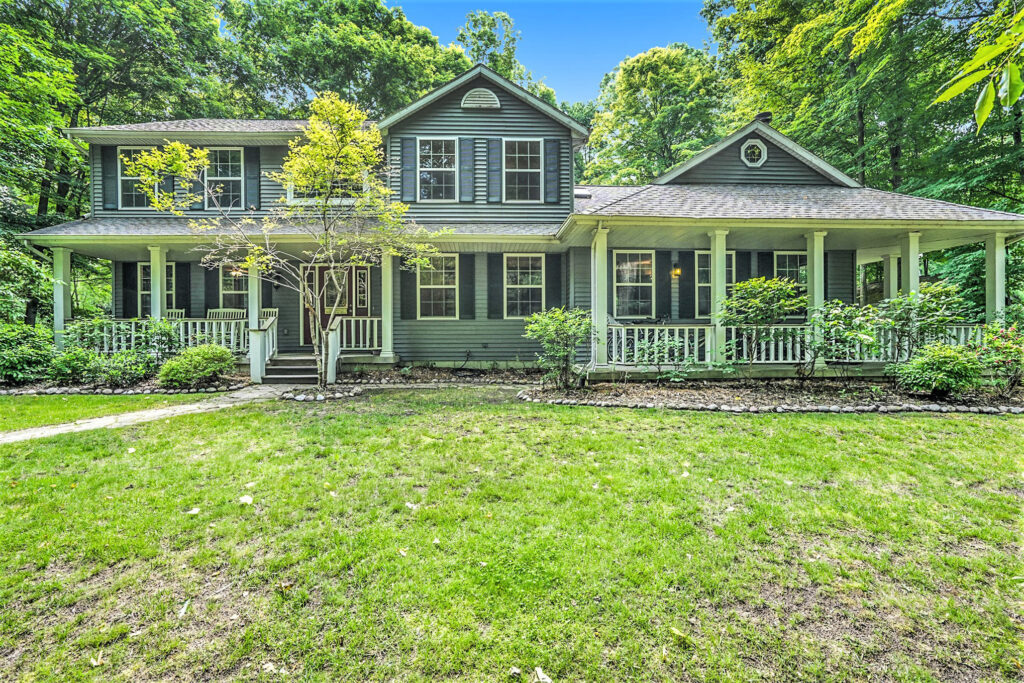 Two-story green house with porch and garden