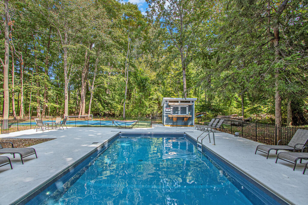 Outdoor swimming pool surrounded by trees and lounge chairs