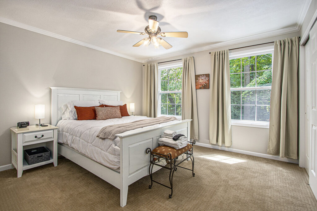 Bright bedroom with white furniture and large windows